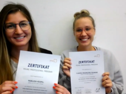 Digitaler Abschlussworkshop: Marleen und Claudia halten ihre Zertifikate in die Kamera. 
